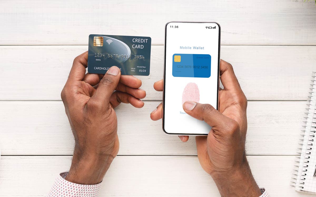 Hands holding a credit card and a smartphone, logging into a financial app with a fingerprint