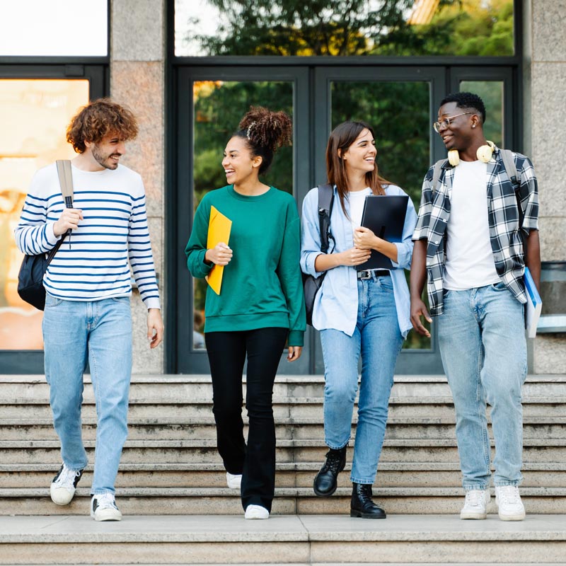 Group of four college students walking down the steps of the library