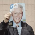 Person holding a magazine with a portrait of famous politician on it, using it as a mask.