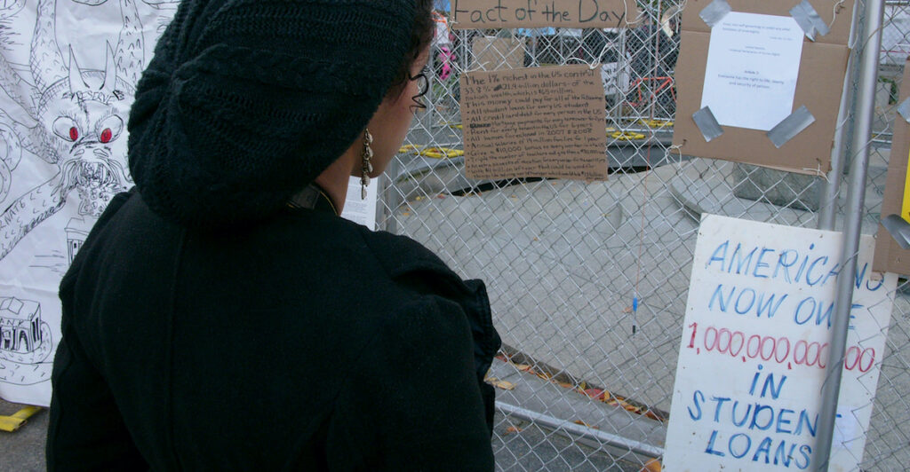a lady looking at hanging sign about student debt